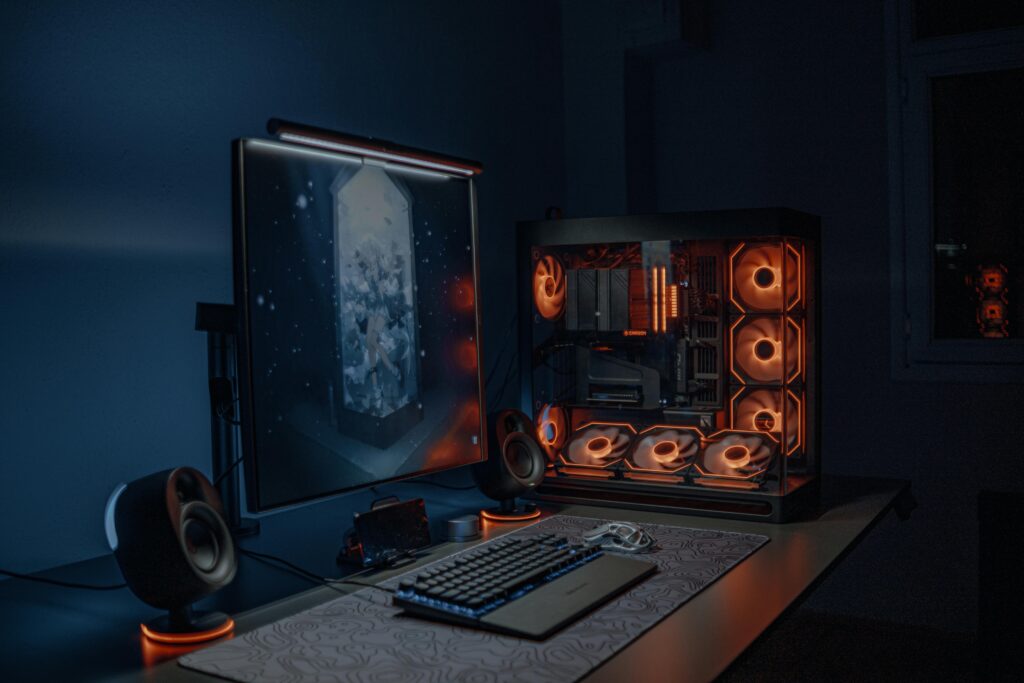 A sleek gaming PC setup with LED lights, monitor, and keyboard in a dimly lit room.